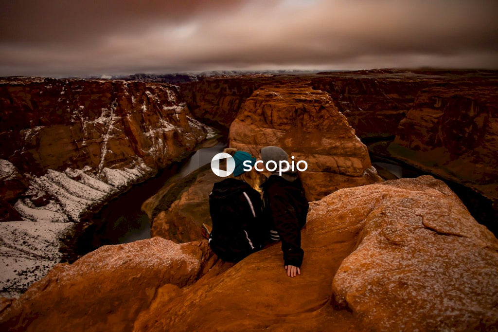 A couple kissing while sitting atop a mountain