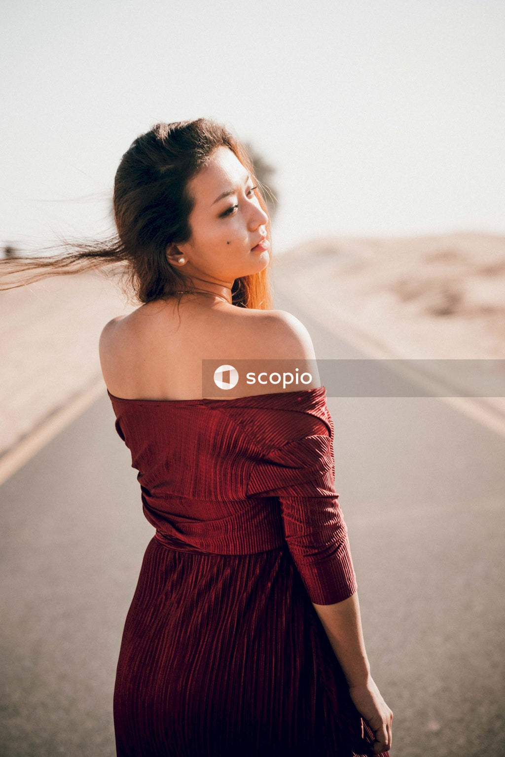 Back view of woman wearing red dress standing on road
