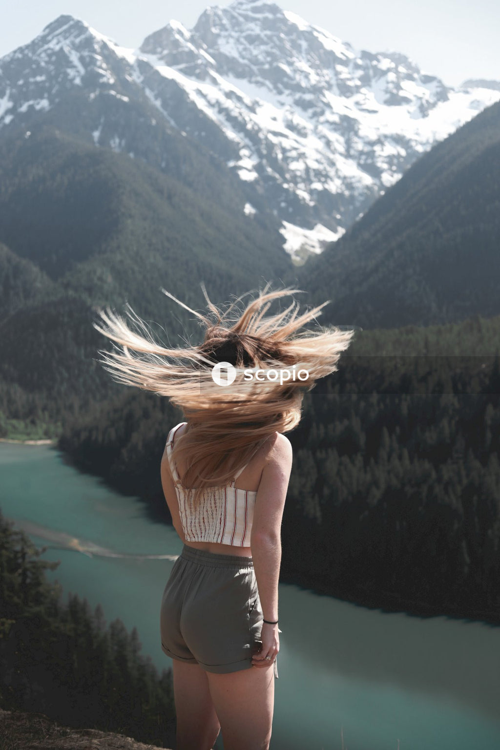 Back view of young woman flipping her hair standing near Diablo lake in Washington, US