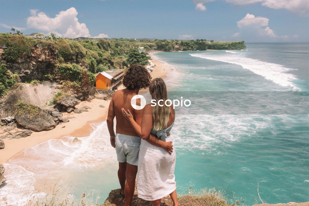Man and woman standing on rocks looking at the ocean