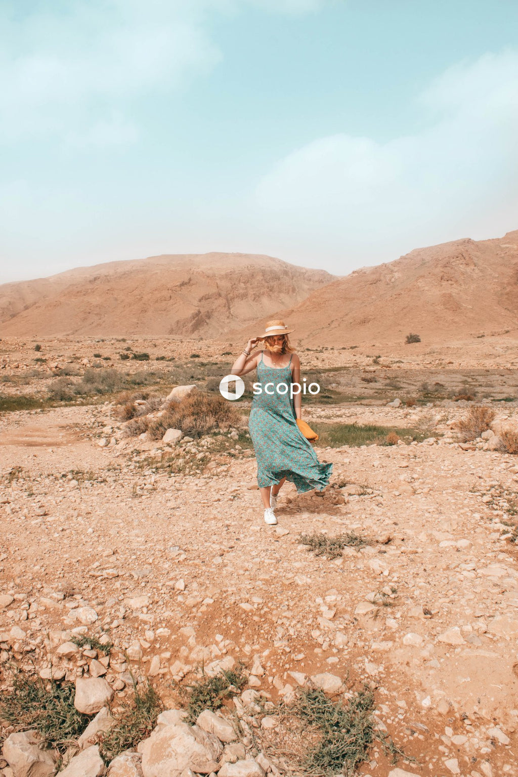 Woman in green sleeveless dress walking on brown dirt road