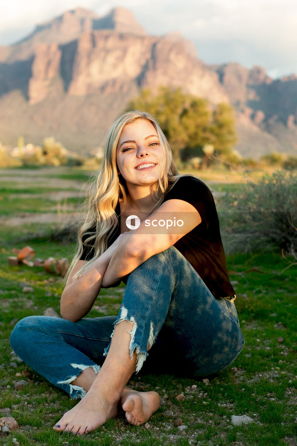Woman in black shirt and blue denim jeans sitting on green grass field