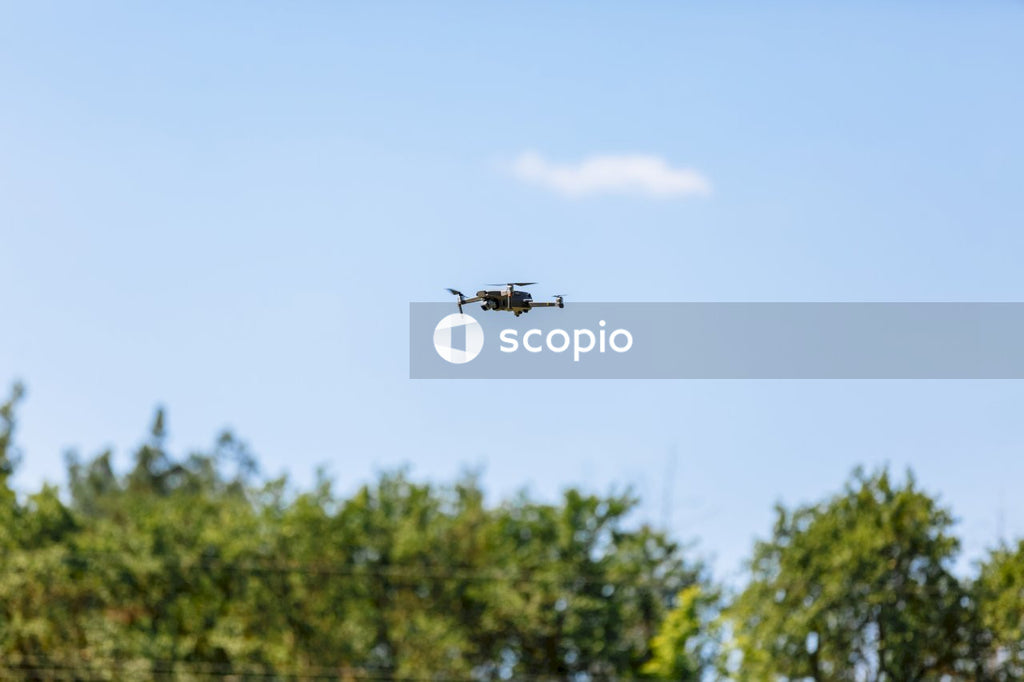 Black helicopter flying over green trees