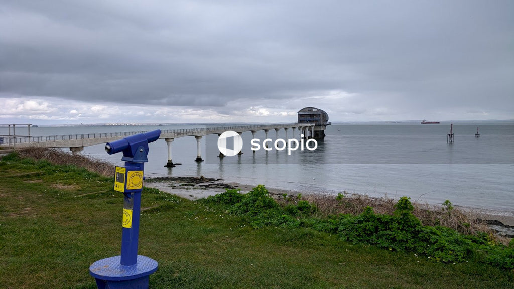 Blue and white metal post near body of water under white clouds