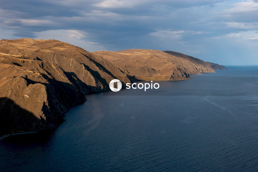 Brown and green mountain beside body of water