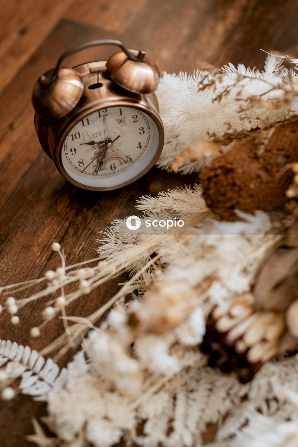 Brown and white analog alarm clock on brown wooden table