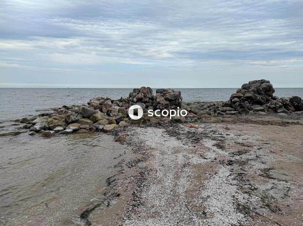 Brown rocks on seashore under white clouds
