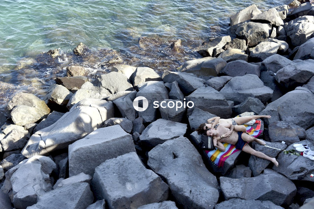 Young couple laying on boulders at the beach