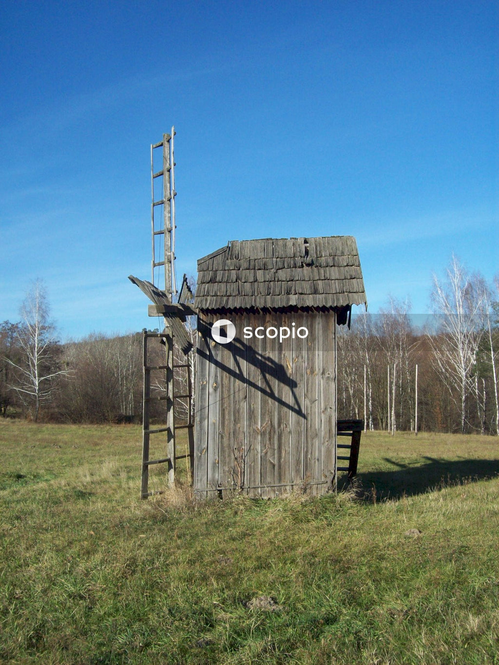 Brown wooden barn on green grass field under blue sky