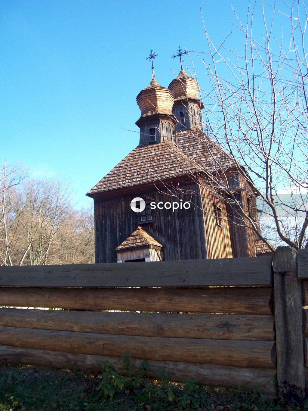 Brown wooden house near bare trees under blue sky