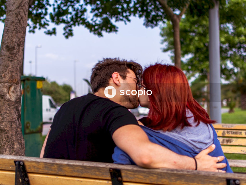 Man and woman kissing on brown wooden bench