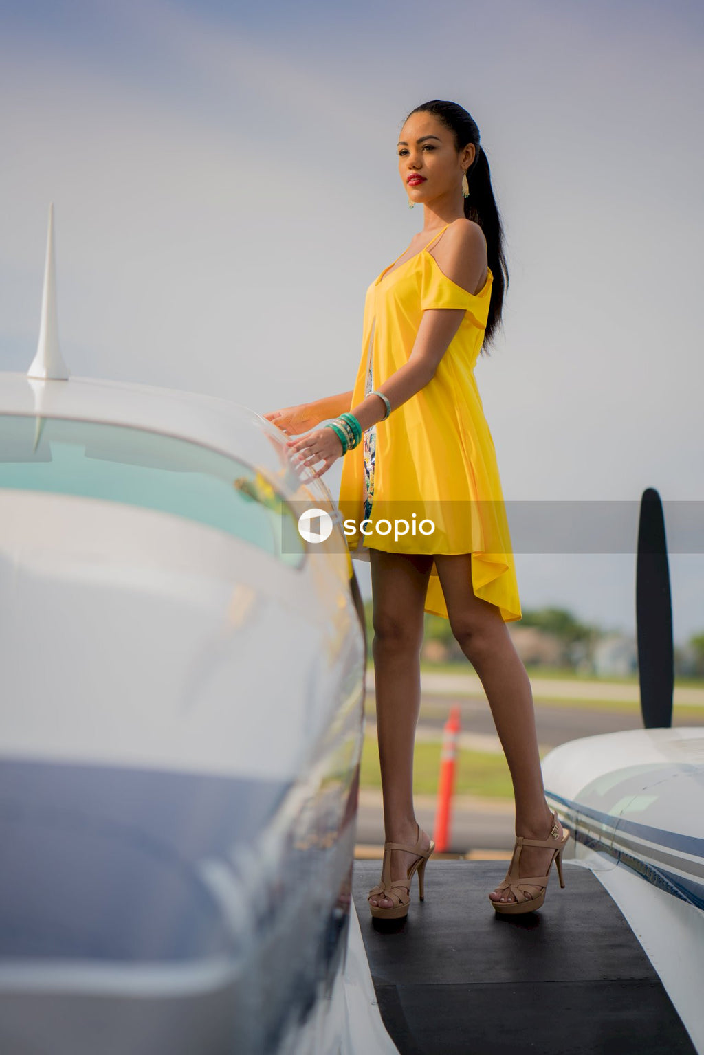 Woman in yellow dress standing beside plane roof