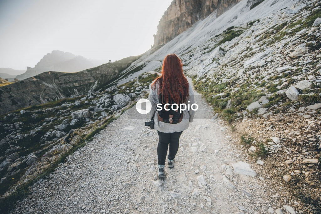 Woman in white jacket and black pants walking on dirt road