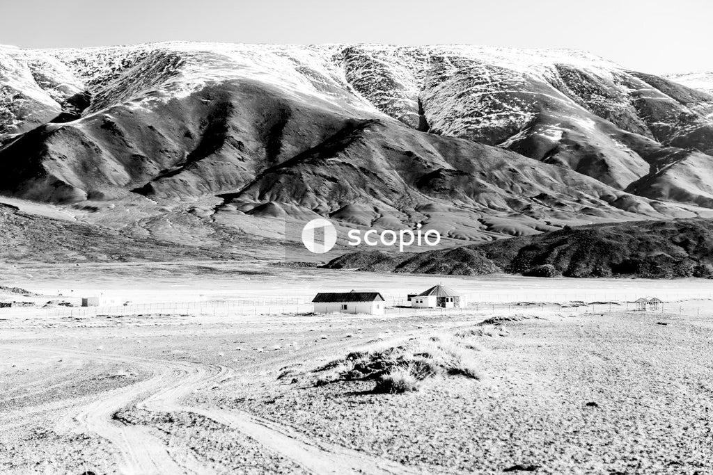 Grayscale photo of house near mountain
