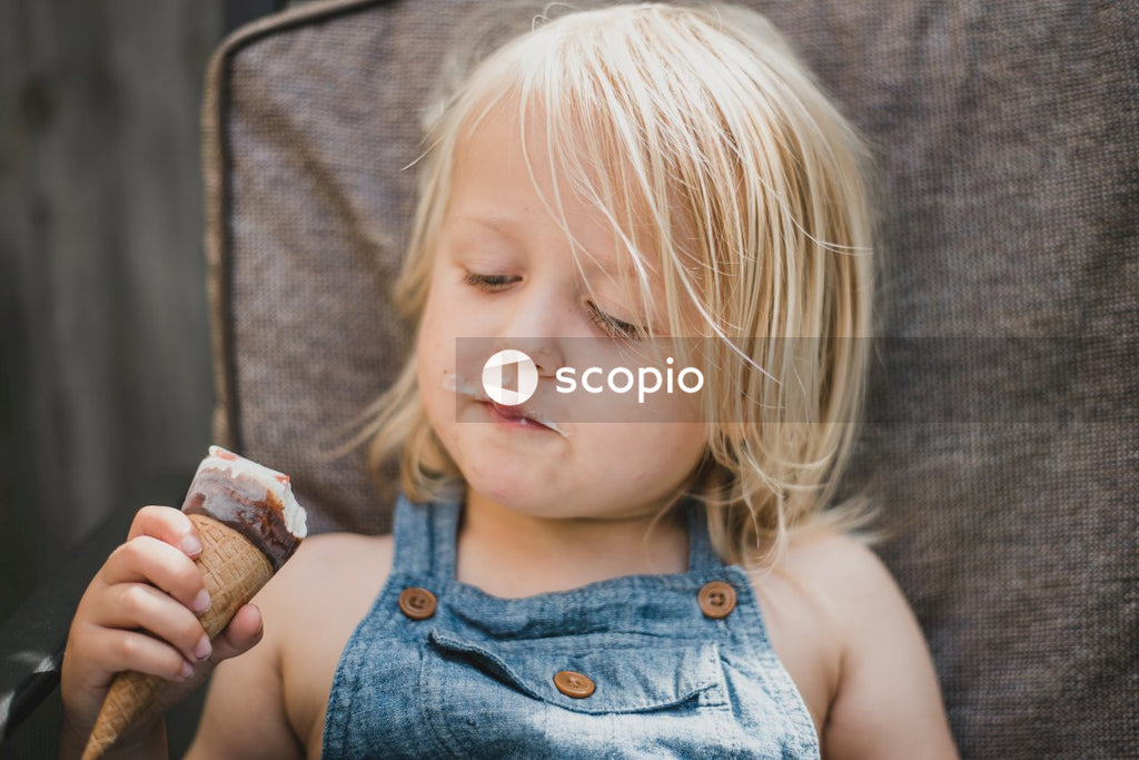 Happy Kid in Denim Overall Dress Enjoys Scoop of Ice Cream