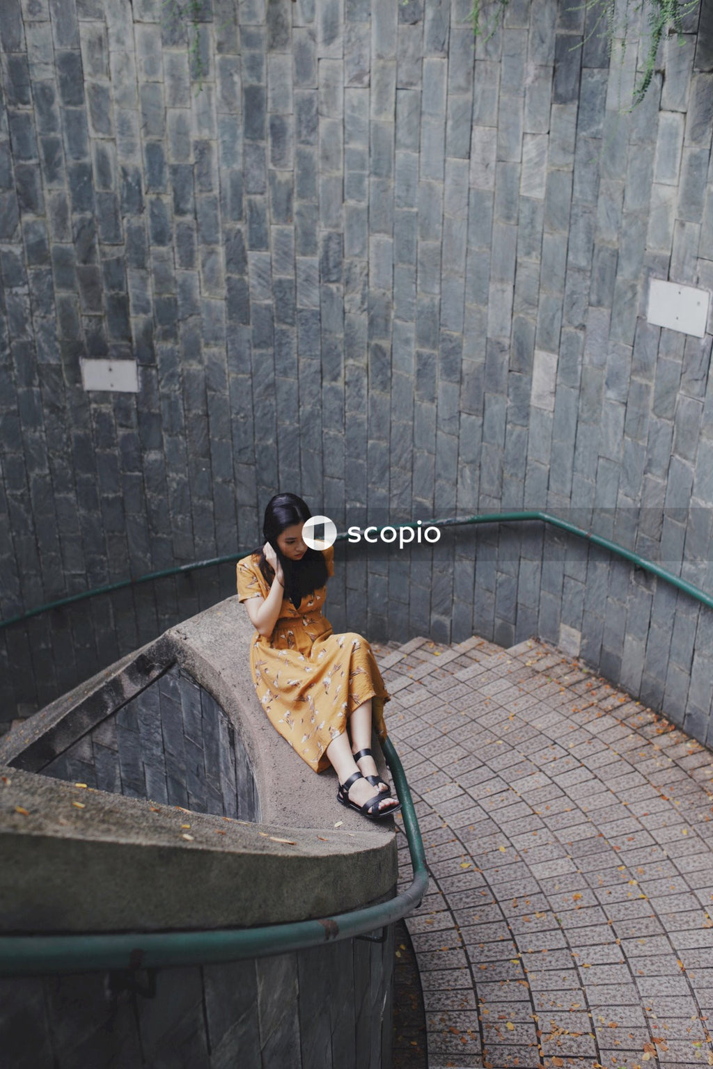 Asian woman in orange dress sitting on bannister