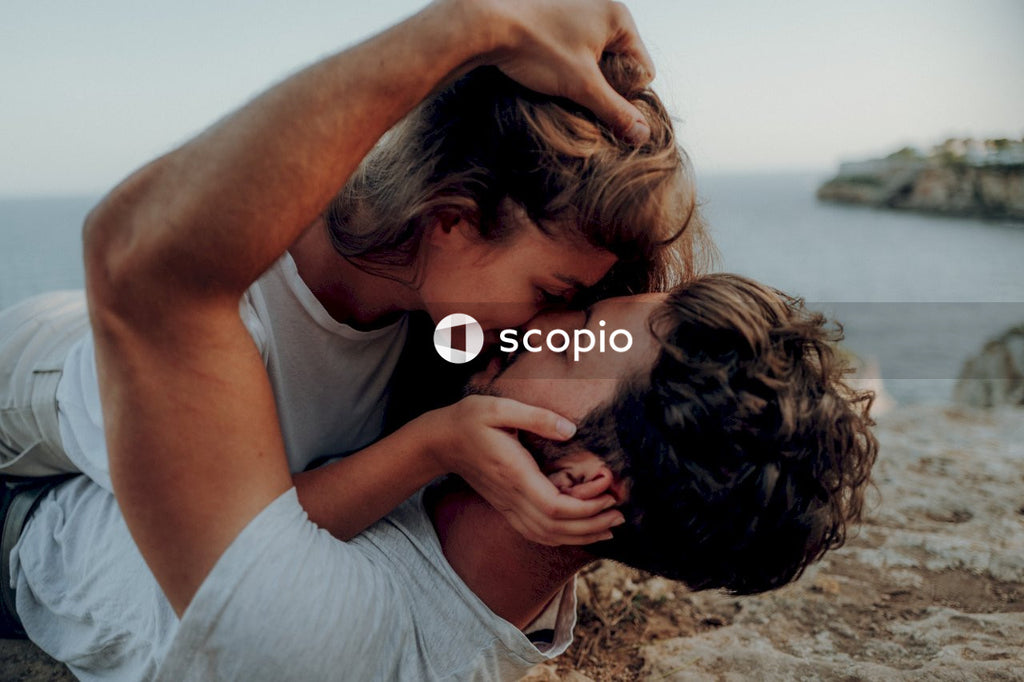 Man and woman kissing and laying on seashore