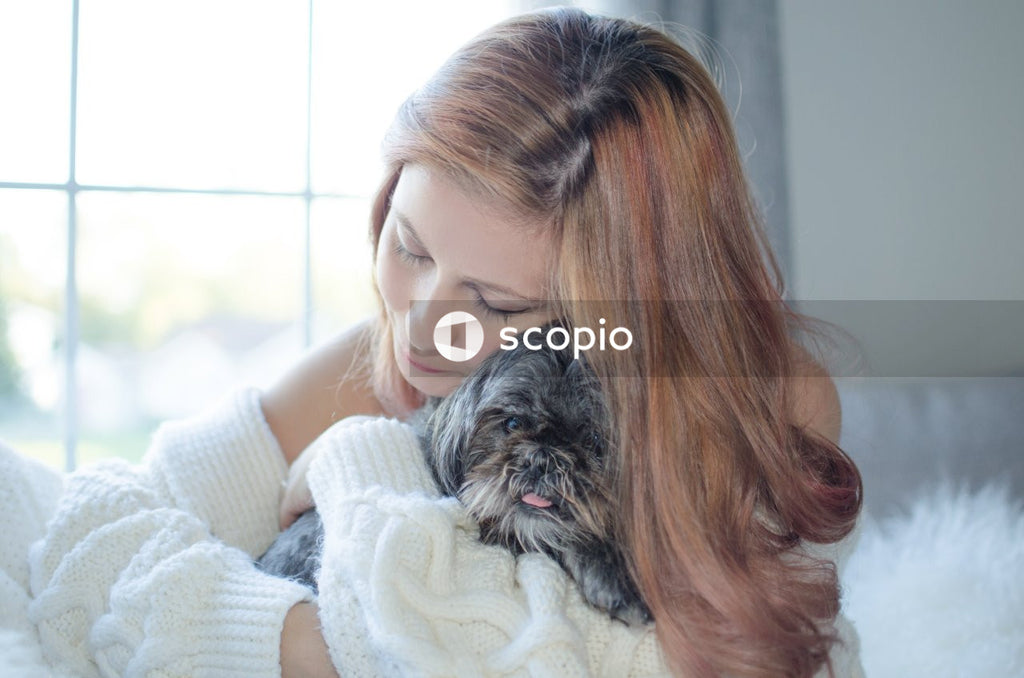Woman wearing white sweater hugging small dog