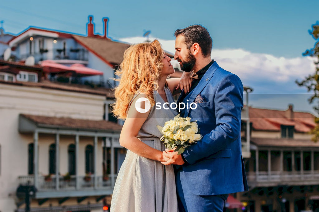 Man in black suit kissing woman in white dress