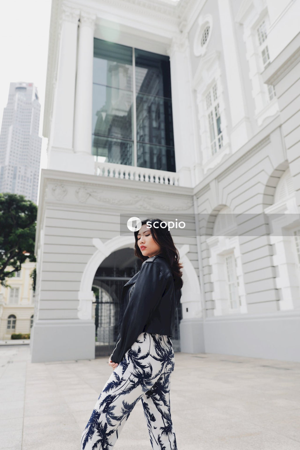 Woman in  jacket standing near white concrete building
