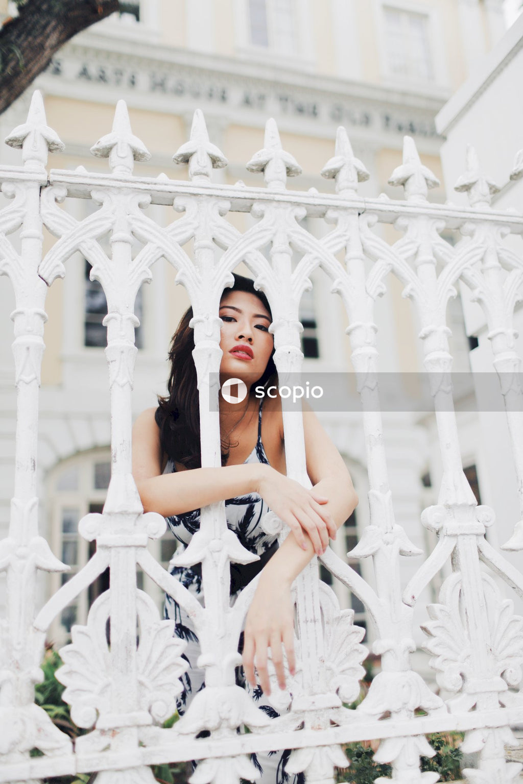 Woman in black tank top leaning on white wooden fence