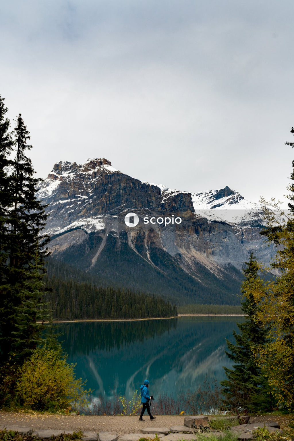 Person walking by the lake near snow covered mountain