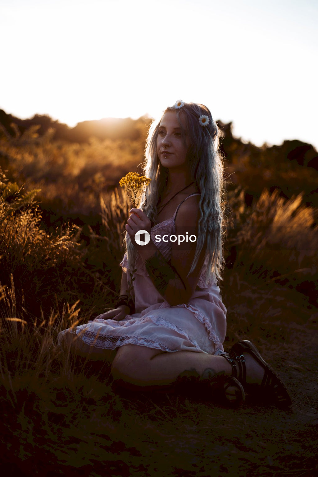 Woman in white long sleeve dress sitting on brown grass field
