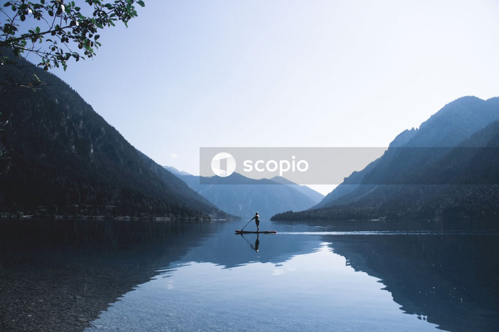 Person kayaking in lake surrounded by mountains