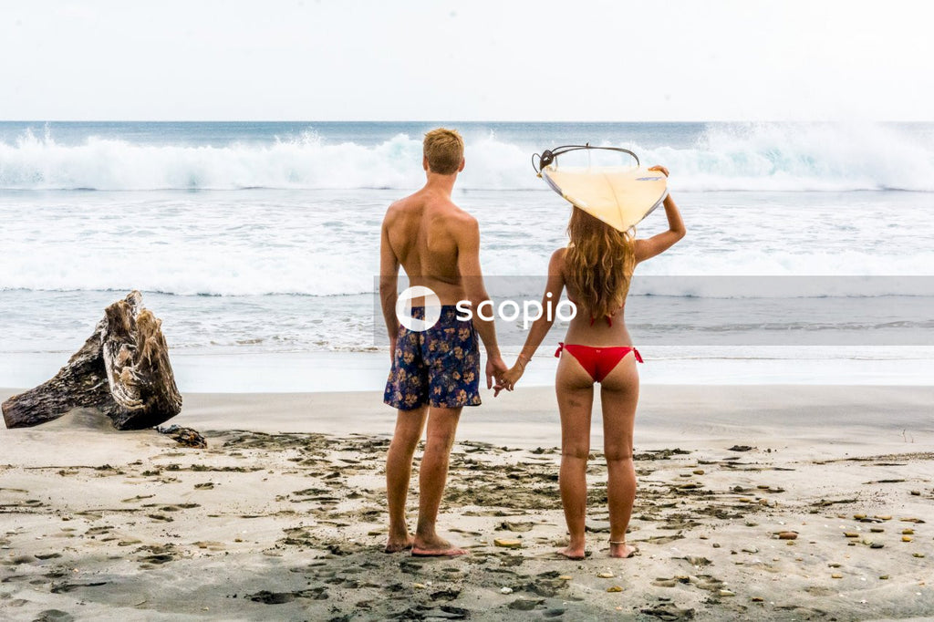Couple holding hands while facing beach