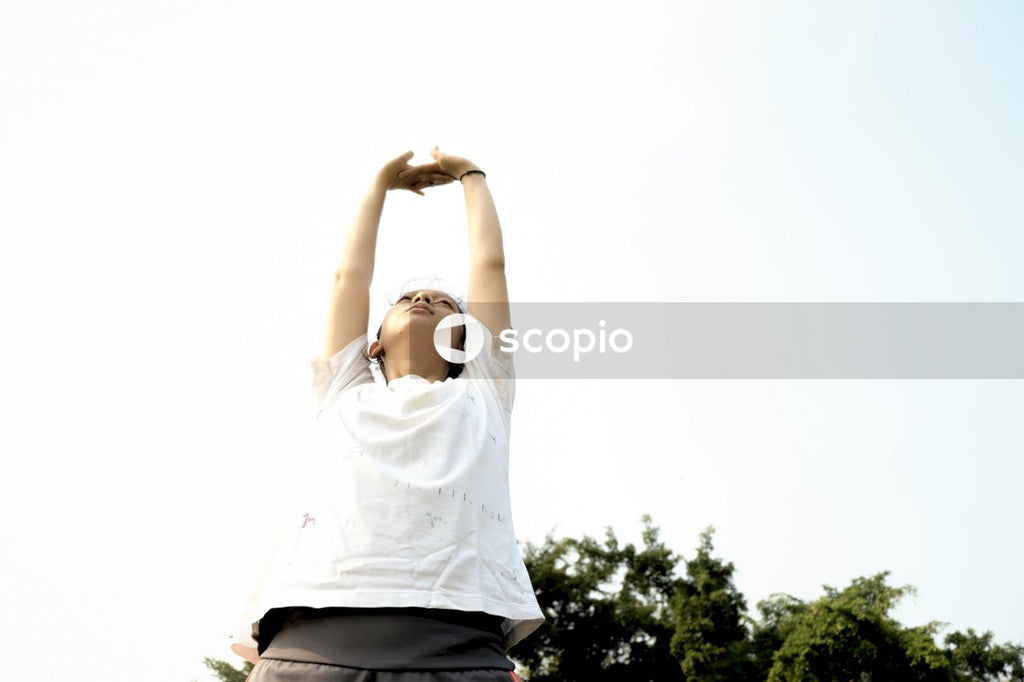 Woman in white crew neck t-shirt raising her hands
