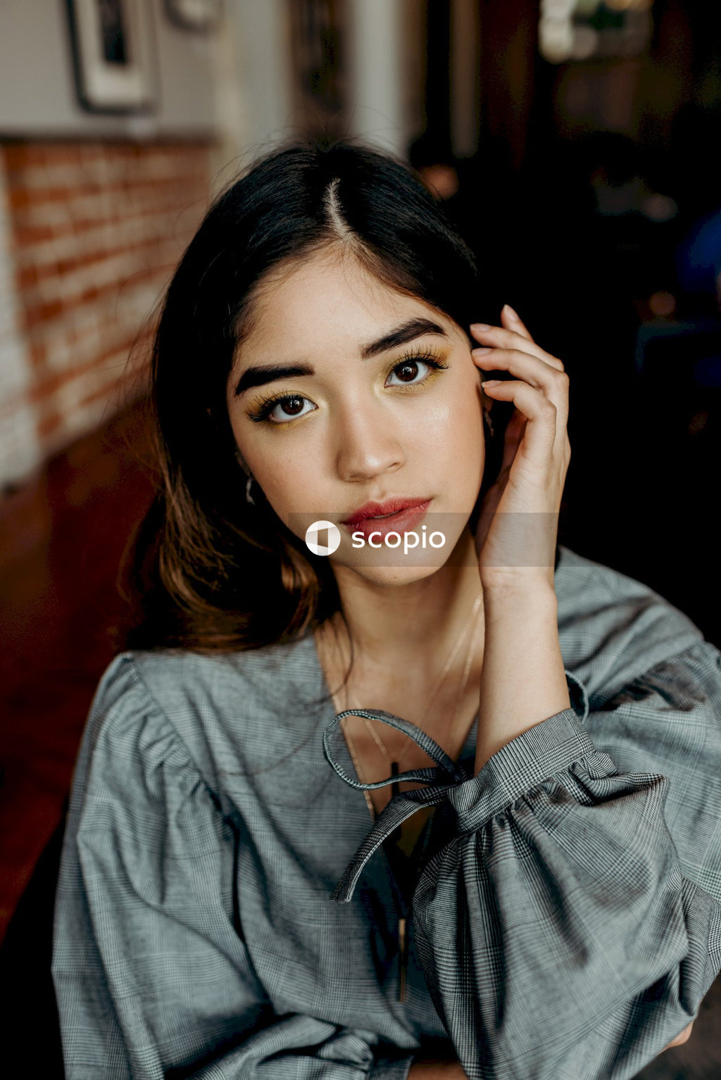 Portrait of woman in gray shirt with her hand on her face