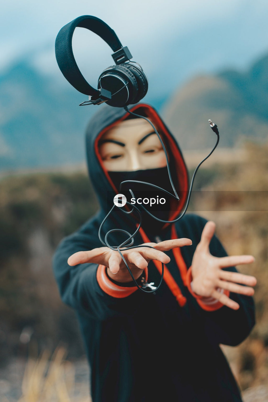 A Person in a mask holding a black headphones