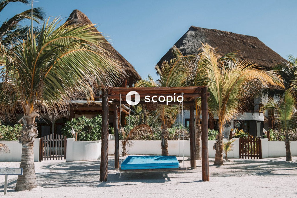 Wooden beach bed near palm trees and bungalows