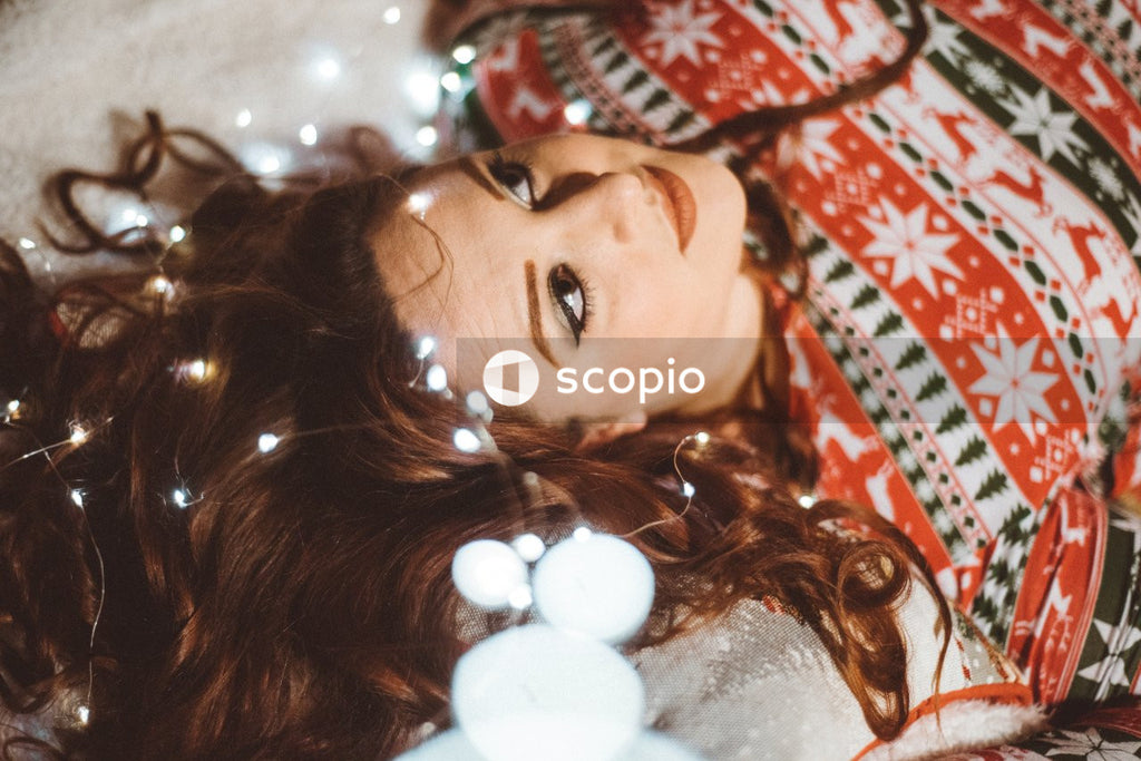 Woman in Christmas shirt lying and surrounded by string light