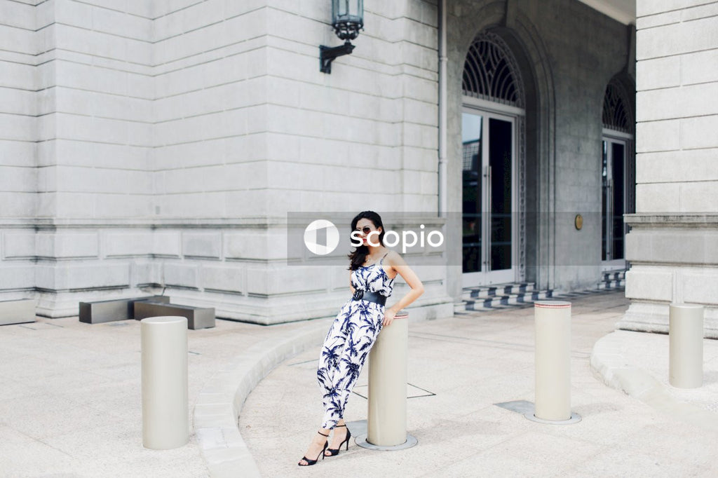 Woman in light and dark jumpsuit posing in front of building