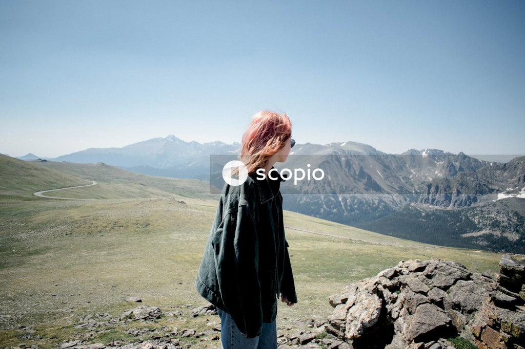 Woman in denim jacket standing on brown field near mountains