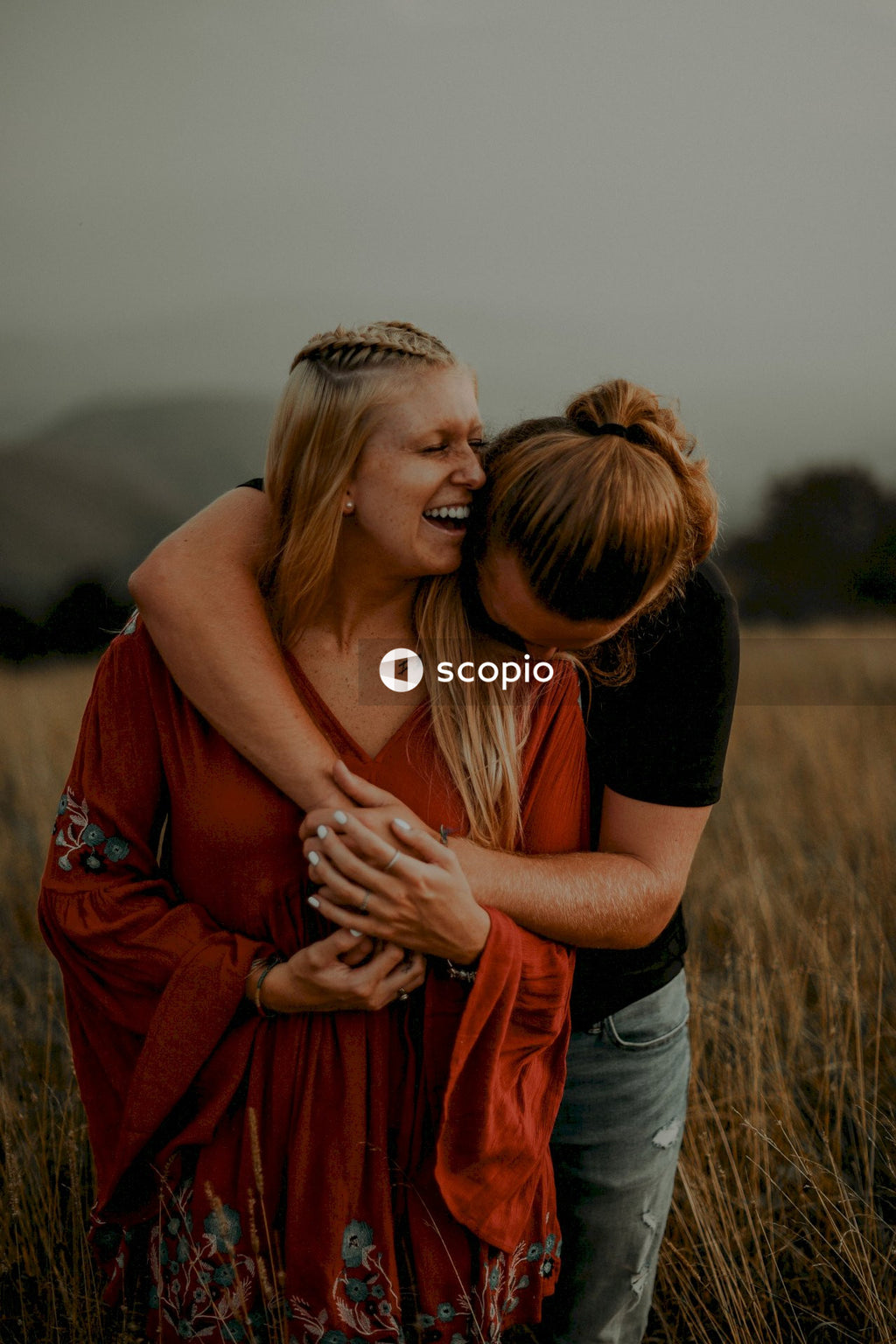Man in black t-shirt hugging woman in red dress
