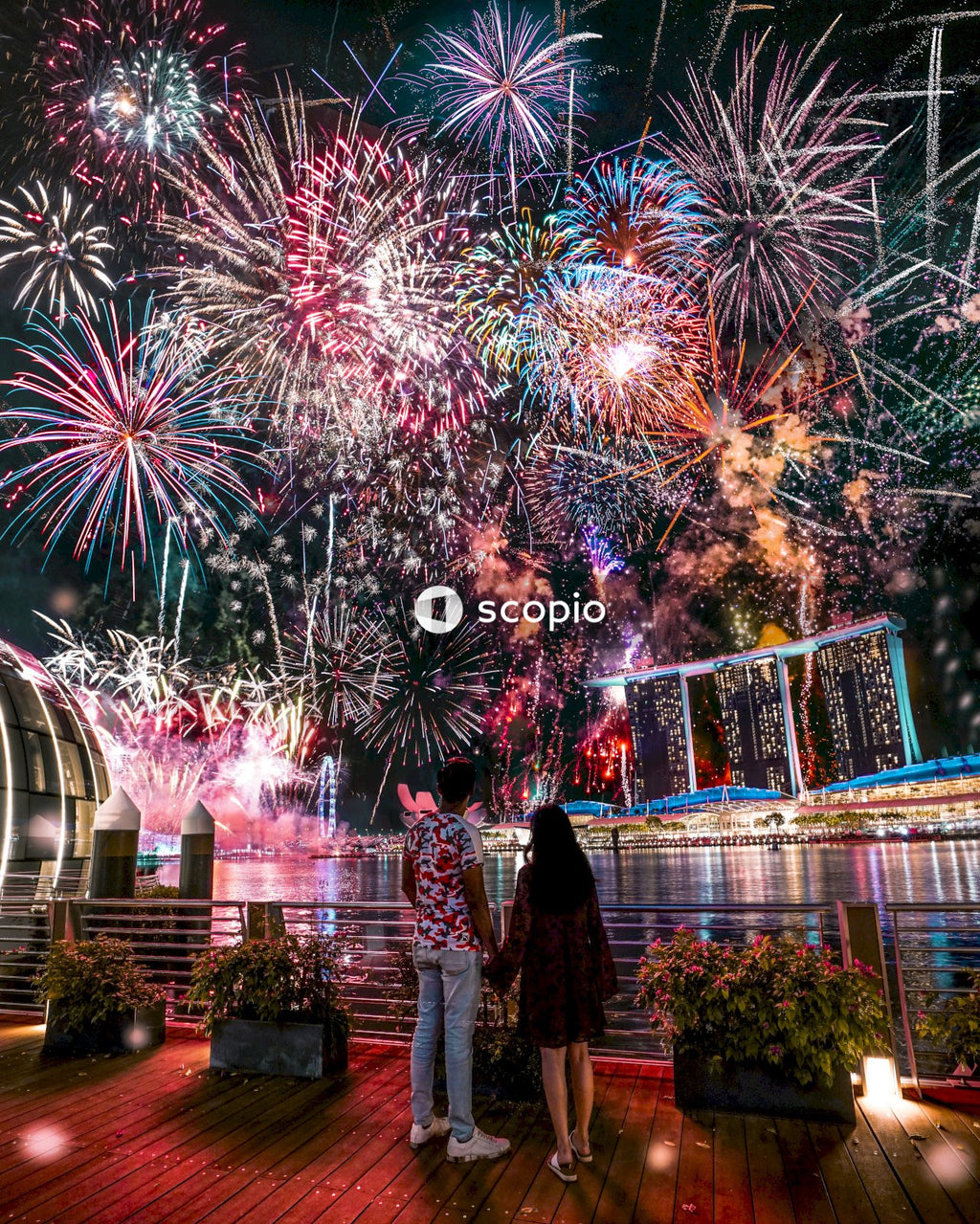 Couple standing at the harbor watching fireworks display