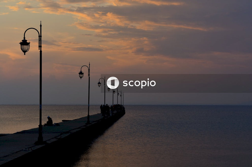 People walking on wooden dock during sunset