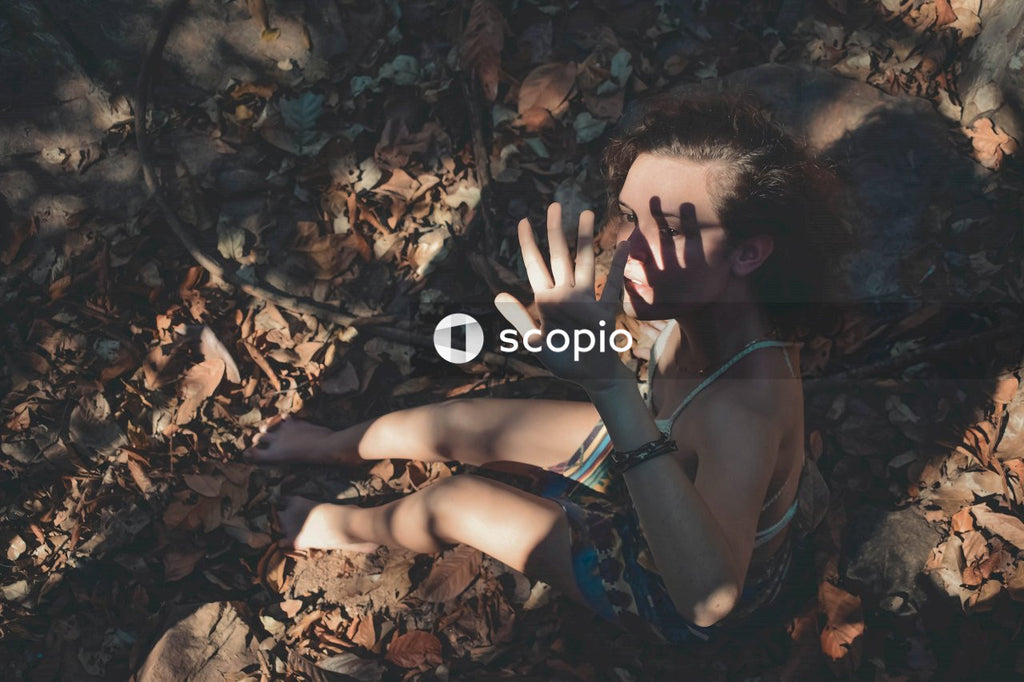 Woman sitting on brown tree leaves blocking the sun light with her hand