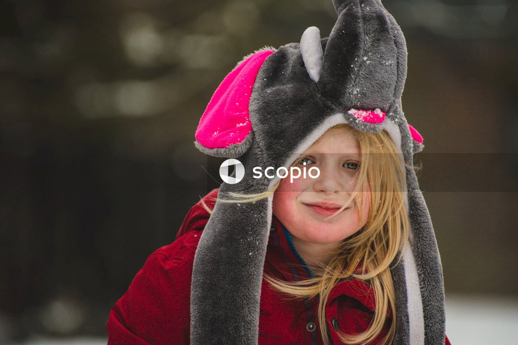 Portrait of young blonde boy with long hair wearing elephant hat