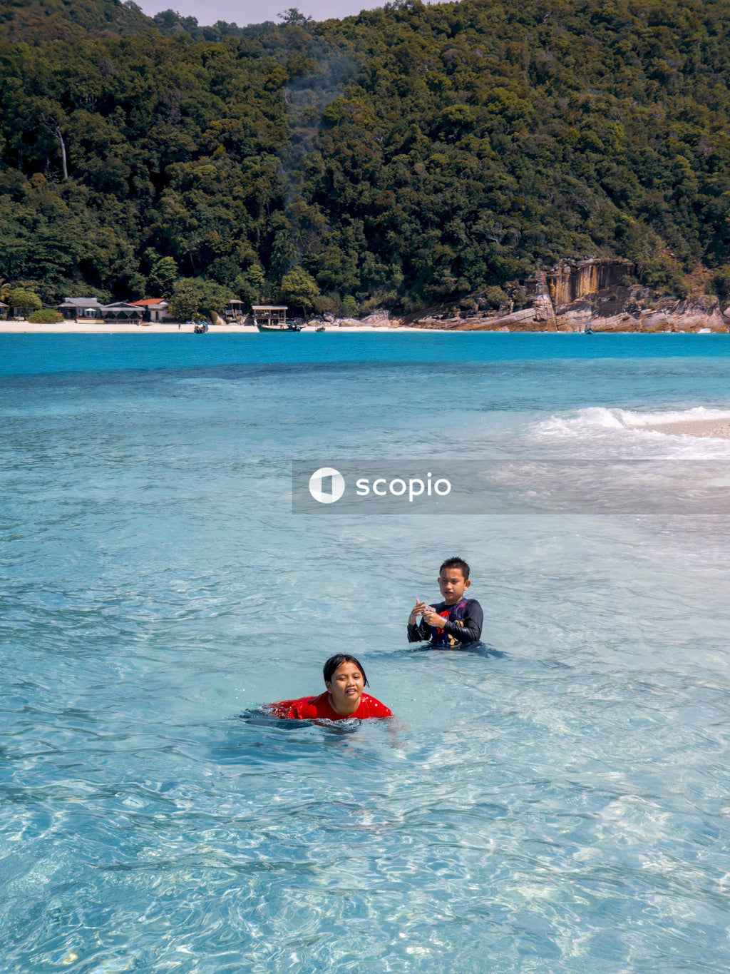 Children in red and black swimsuit lying on water