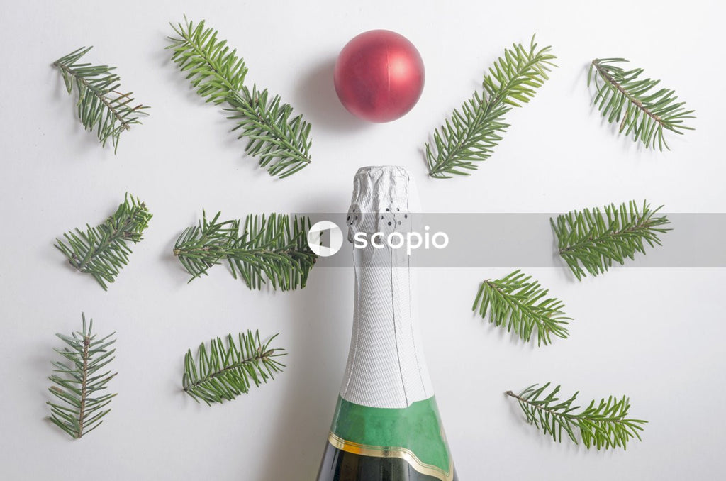 Christmas composition.A bottle of vine,red ball and many fir tree branches on white background.Top view,flatlay.