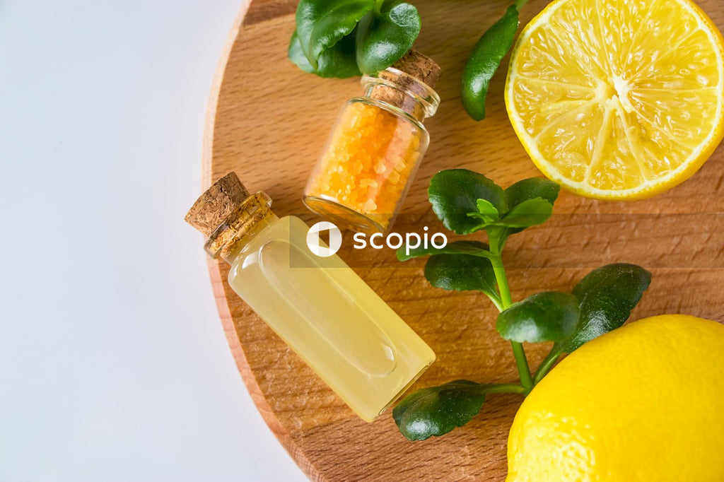 Clear glass bottle with orange juice beside sliced lemon on brown wooden table