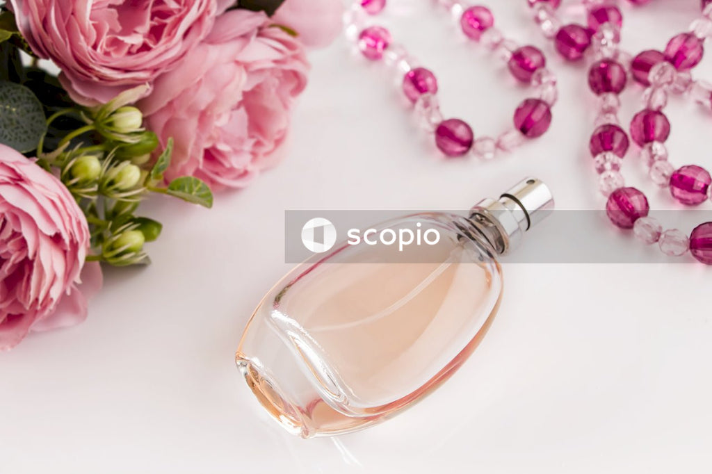 Clear glass perfume bottle beside pink flowers