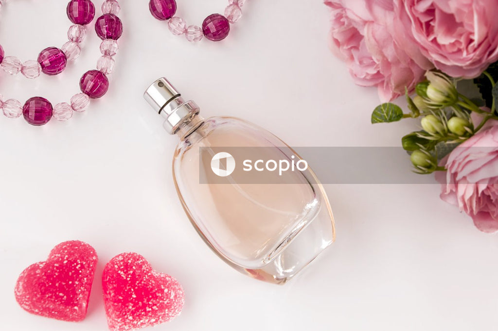 Clear glass perfume bottle beside pink rose
