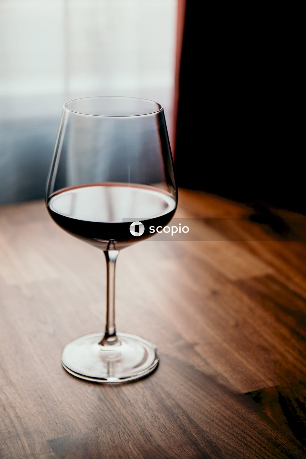 Clear wine glass with red wine on brown wooden table