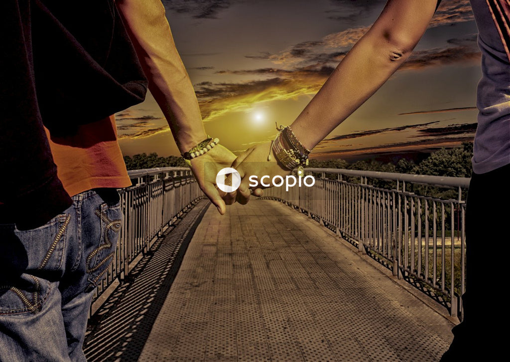 Couple holding hands while walking on bridge during sunset