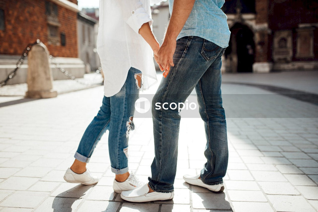 Couple holding hands while walking on sidewalk