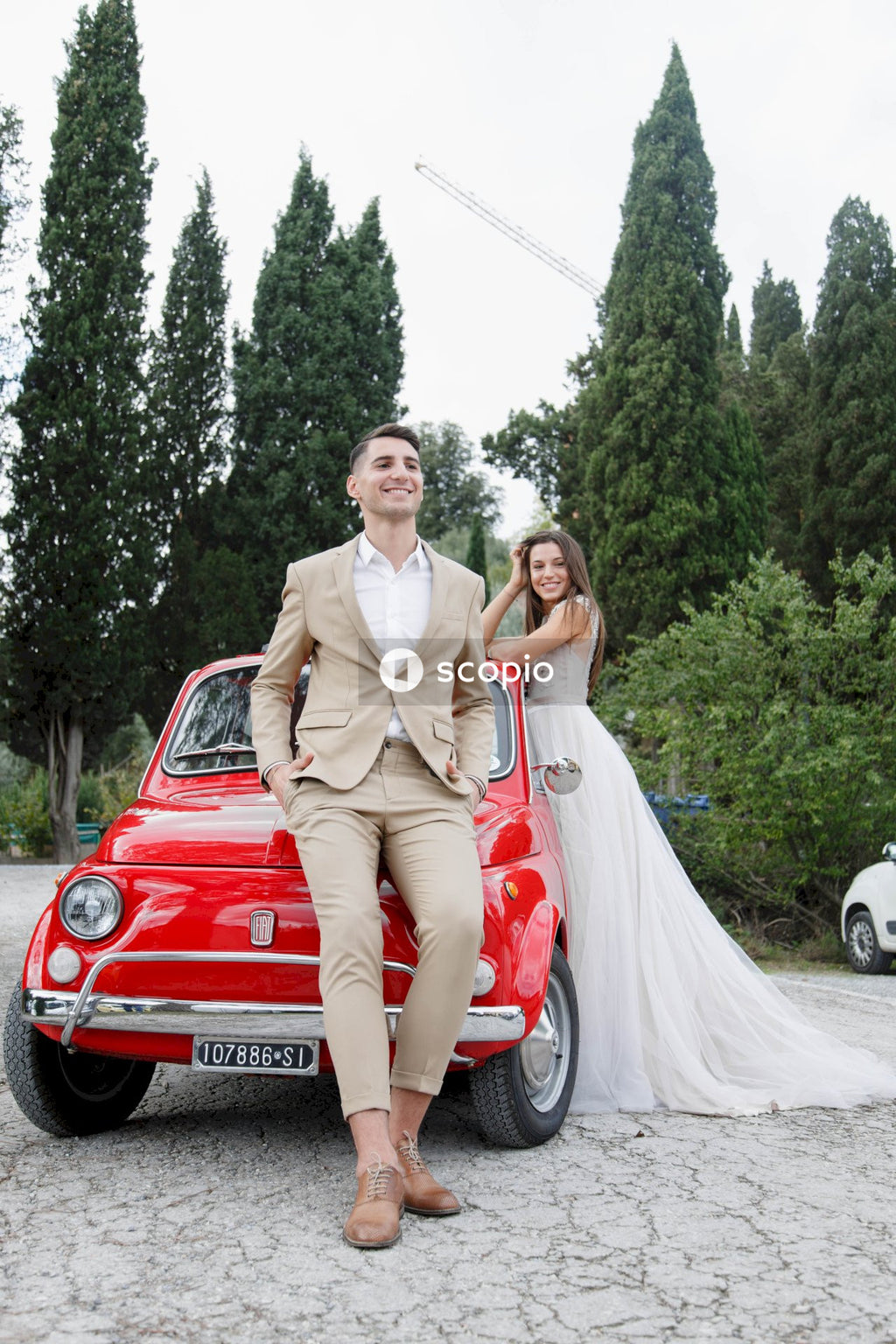 Young married couple doing a photoshoot near small red car